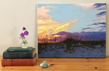 Load image into Gallery viewer, acrylic painting of peach, gold, and purple sunset in front of pale blue sky over darkening sand dunes with sea oats next to books and vase of flowers